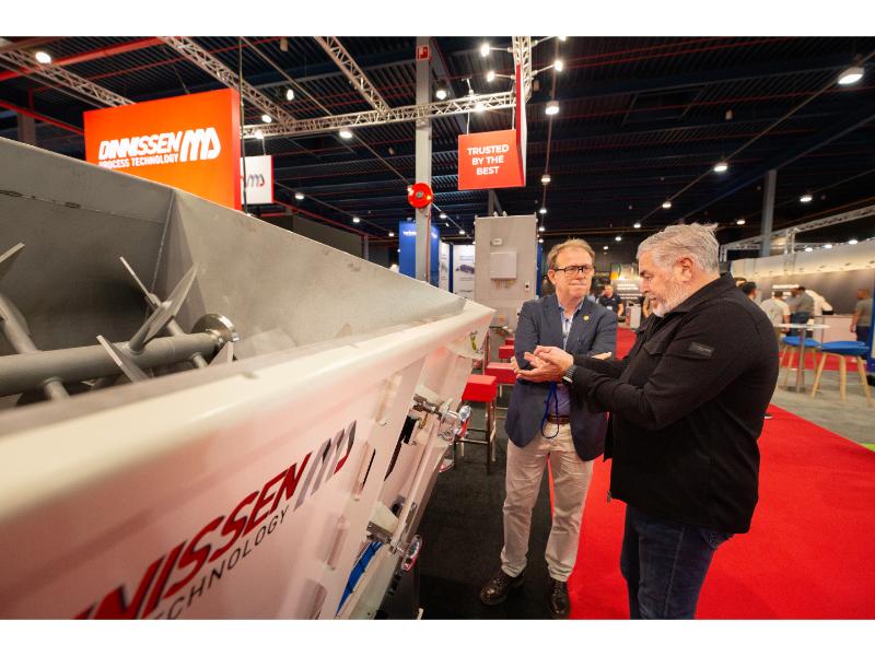 De stand van Dinnissen met op de voorgrond algemeen directeur Frans Bakker die uitleg geeft aan een bezoeker over deze paddle-mixer 

